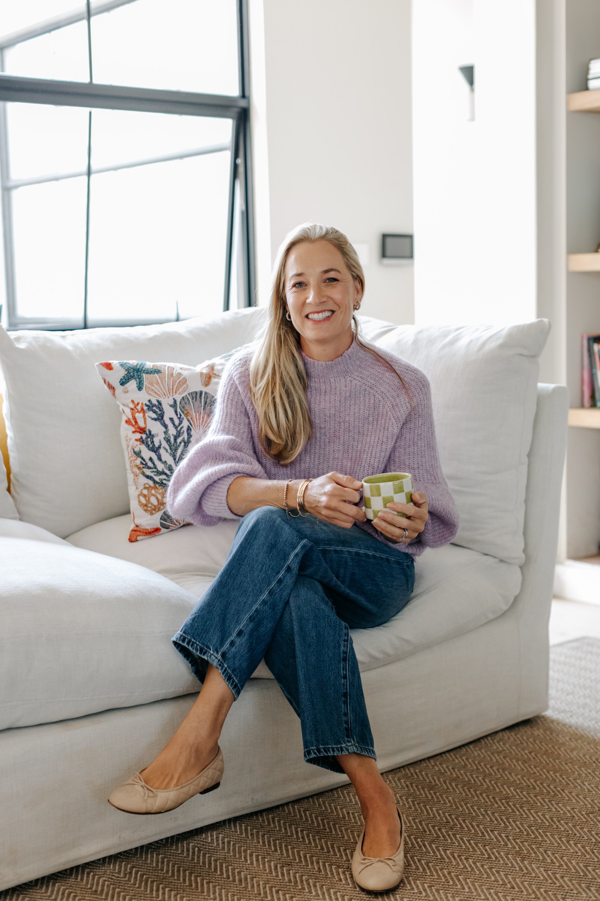 Sarah Reuter seated on a sofa holding a mug